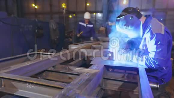 焊接设备产生的光亮火花店里有两个人在做金属工作车间总图中工作流程视频的预览图