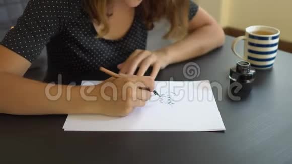 一位年轻女子用刻字技巧在纸上书写书法的特写镜头她写的更多视频的预览图