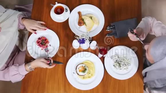 两个穆斯林妇女坐在餐馆里提供简单菜肴视频的预览图