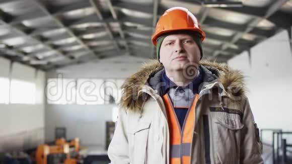 戴着安全帽穿着工作服的人正站在机库的中间双手放在摄像机的胸前视频的预览图