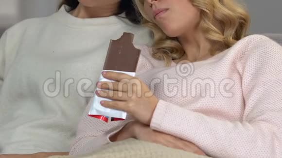 美丽悲伤的女孩吃巧克力坐在一起平静和放松PMS视频的预览图