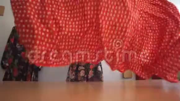 一位白种人的女人在慢动作中摇晃并在桌子上铺上带有白色圆点的红色织物视频的预览图