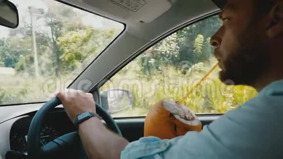 在车内拍摄轻松的商人与智能手表驾驶汽车享受异国情调的水果饮料暑假视频的预览图