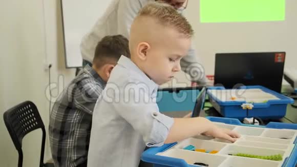好奇的白种人孩子在慢动作课堂上体验如何构建塑料机器人玩具视频的预览图