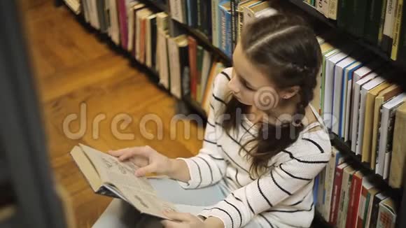 女孩坐在地板上翻阅一本书视频的预览图