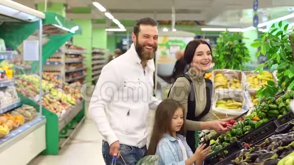 一个年轻的家庭有一个可爱的女儿在超市买蔬菜视频的预览图