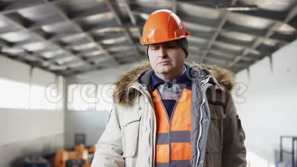 戴着安全帽穿着工作服的人正站在机库的中间对着摄像机对着钻视频的预览图