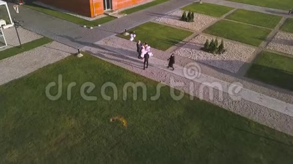 户外婚礼照片空中表演艺术新婚夫妇带着孩子在两名摄影师面前摆姿势视频的预览图