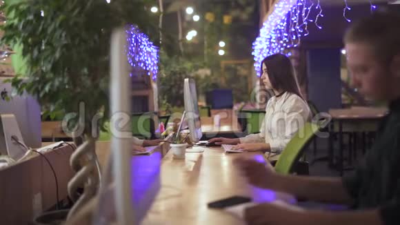 一个坐在前台桌子旁的年轻人关注的是从事现代工作的漂亮女人视频的预览图