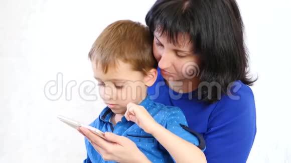 幸福家庭妈妈和儿子拿着智能手机在网上玩孩子的申请一代人视频的预览图