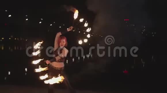 熟练的女消防队员在河边旋转燃烧的扇子视频的预览图