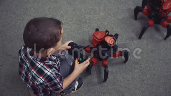小男孩坐在地板上用遥控器参与机器人的战斗视频的预览图