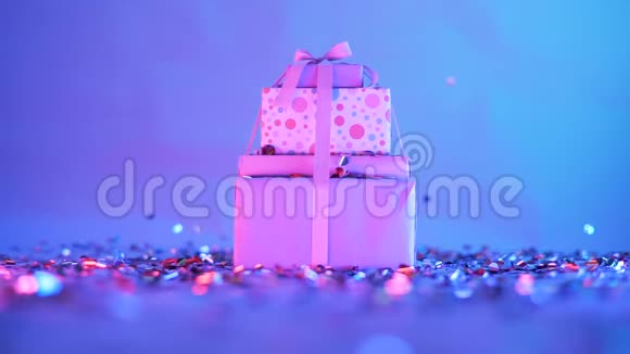 精美包装的礼物在霓虹灯中拍摄五颜六色的纸屑落在礼物上金属五彩纸屑闪烁在视频的预览图