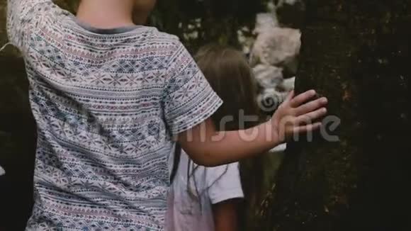 特写镜头跟随两个小孩小心翼翼地踩着大石头从斯里兰卡丛林瀑布上走下来视频的预览图