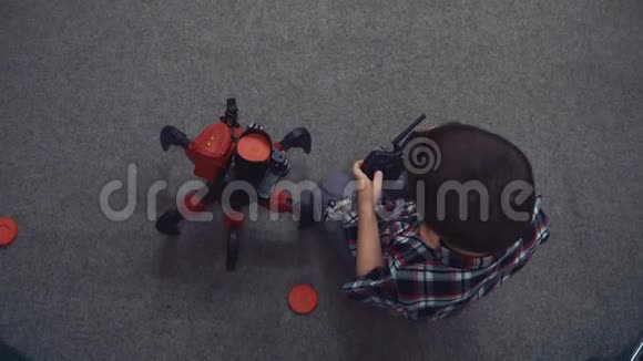 小男孩坐在地板上用遥控器操作机器人机器人的六条腿发射磁盘视频的预览图