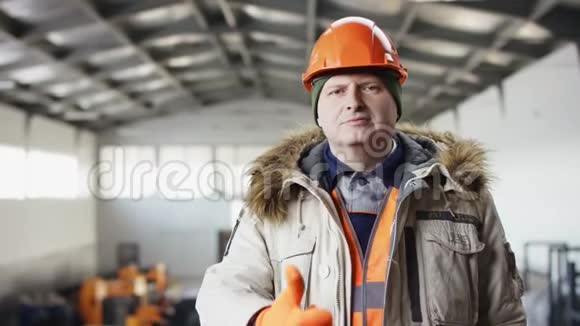 戴着安全帽穿着工作服的人正站在机库中间对着镜头竖起大拇指视频的预览图