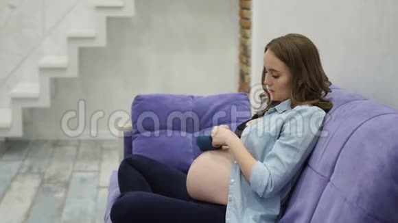孕妇在家坐在扶手椅上给宝宝玩可爱的小袜子建议这样可以帮助宝宝视频的预览图