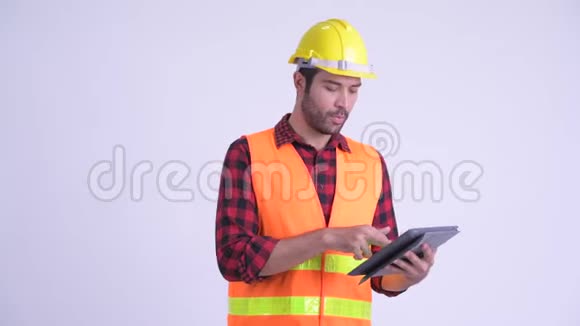 英俊留胡子的波斯人建筑工人在使用数码平板电脑时指挥视频的预览图