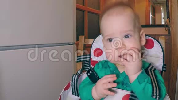 小可爱的小男孩有两颗较低的牙齿吃着吸管看着旁边坐在厨房里视频的预览图