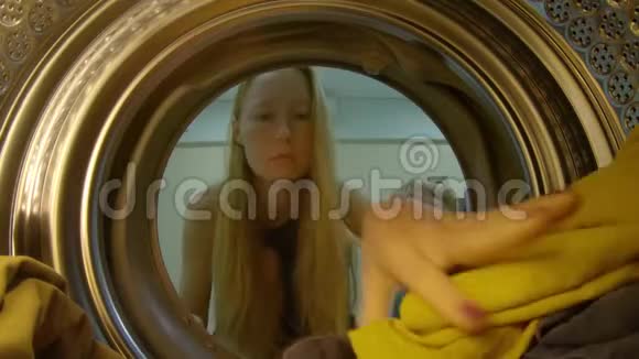 从洗衣机上看年轻女子把脏衣服放进洗衣机视频的预览图