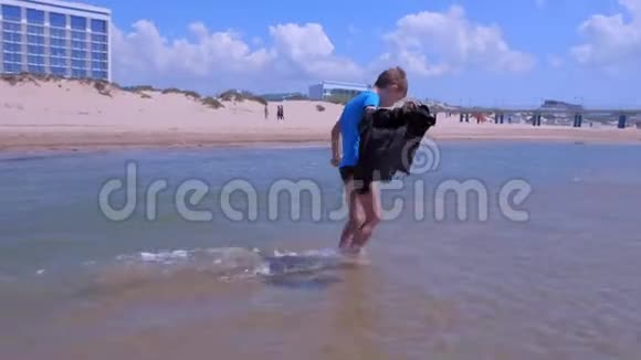 小男孩在海上度假散步在海水中休息在沙滩在风日视频的预览图