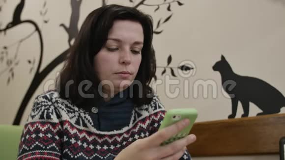 近距离拍摄一个女人坐在猫咖啡馆和冲浪电话墙壁也相应地装饰视频的预览图