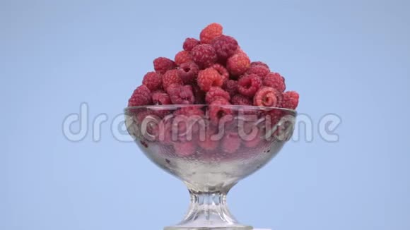 旋转玻璃花瓶与一堆成熟多汁的红树莓视频的预览图