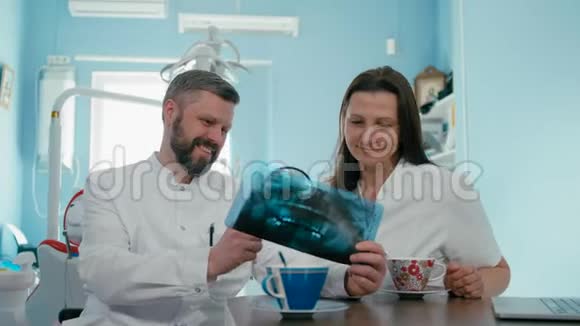两名牙医正在用百叶窗和笔记本电脑检查X光照片视频的预览图