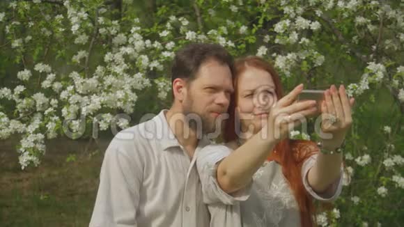 一对相爱的夫妇看着智能手机屏幕上的照片自拍视频的预览图