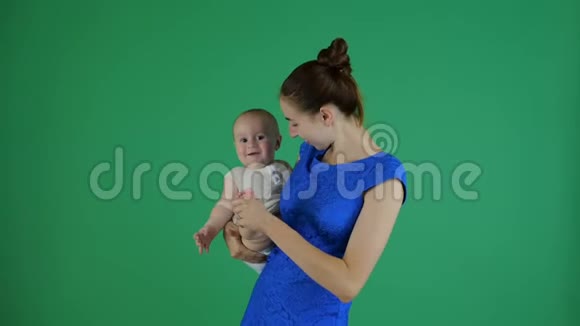 一位年轻的母亲为一个微笑的小婴儿做运动抬起他的腿视频的预览图