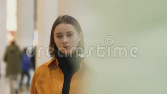 商场里穿着橙色衬衫的漂亮女孩穿过人群视频的预览图