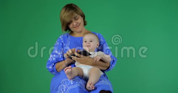 女人用电话抱着孩子宝宝点击智能手机视频的预览图