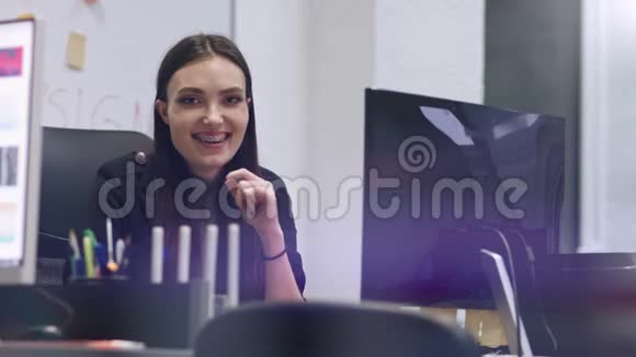 时髦的黑发商务女性对着镜头微笑现代办公室里的女商人慢动作视频的预览图