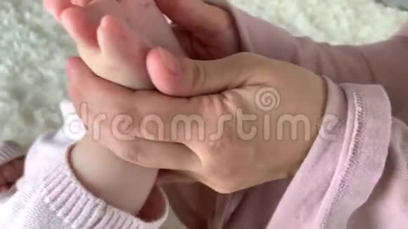 母亲温柔地抱着小女儿的腿做一个轻脚按摩玩耍健康的生活方式快乐的父母视频的预览图