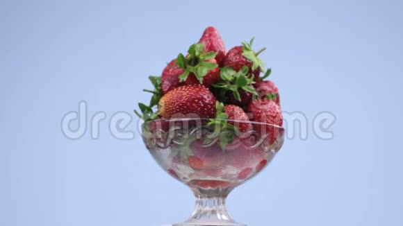 旋转玻璃花瓶与一堆成熟多汁的红色草莓视频的预览图