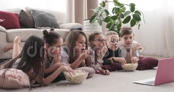 孩子们躺在地板上看电影和吃爆米花视频的预览图