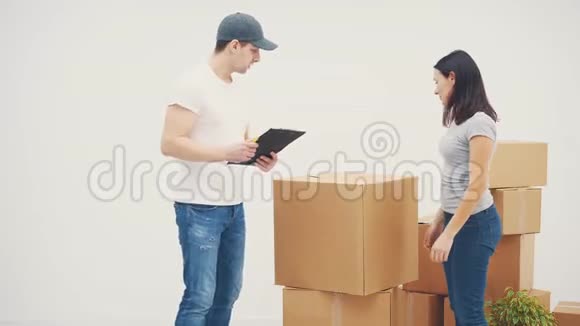 年轻女子搬进新地方她叫一个送货员把所有的纸板箱运到新的公寓里他们视频的预览图