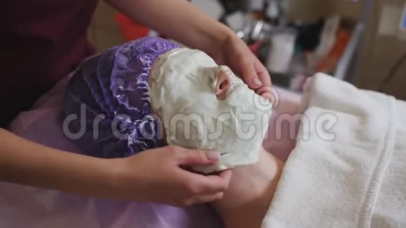 美容师从水疗沙龙的病人脸上取出硬化的面罩视频的预览图
