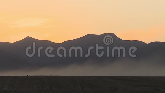 沙尘通过军事装备日落照明山峰和山脊后在沙漠中蔓延视频的预览图