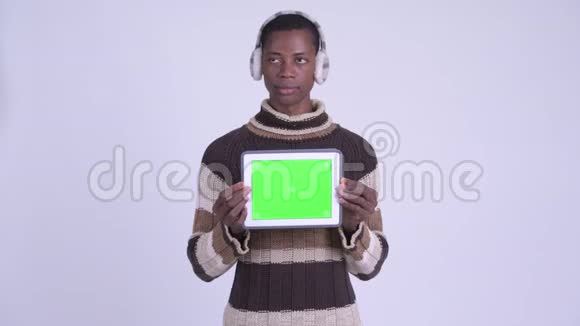 年轻快乐的非洲男人一边思考一边展示数字平板电脑准备过冬视频的预览图