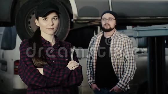 一个漂亮的女孩一个汽车修理工在一个男人的背景下她手里拿着一个扳手她的导师视频的预览图