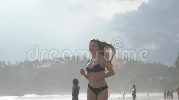 美丽的运动女孩在斯丽兰卡海滩上长发欢乐沿着岸边在水上奔跑视频的预览图