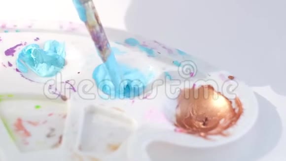 女艺术家用画笔在调色板上混合蓝色颜料视频的预览图