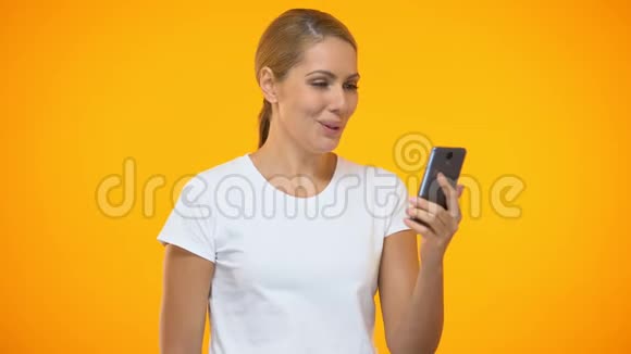 快乐的女士展示持有智能手机在线投注申请信用的美元视频的预览图