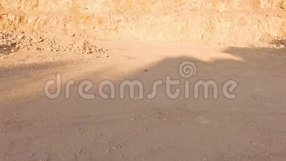 一个年轻的女人光着脚在热沙上穿过沙漠来到一架黄色岩石背景下的白色钢琴前空中飞行视频的预览图