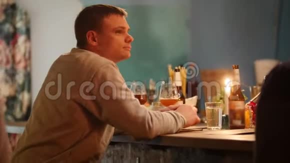 迷人的悲伤男人坐在酒吧里室内灯光柔和一边喝着淡啤酒一边为某人而战视频的预览图