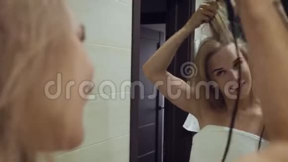 漂亮的女人在浴室洗澡后用刷子烘干机烘干头发视频的预览图