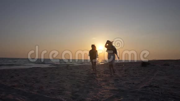 慢动作两个年轻的女人向大海上的夕阳跑去视频的预览图