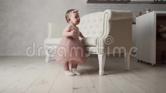 穿着tutu裙和沙发附近衣服的幼儿小女孩学会走路视频的预览图