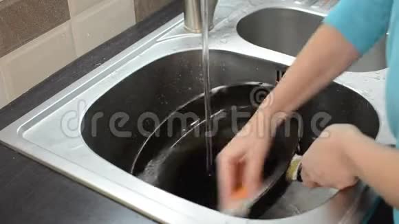 一个女人在洗脸盆里洗了一个装有洗碗剂的平底锅视频的预览图